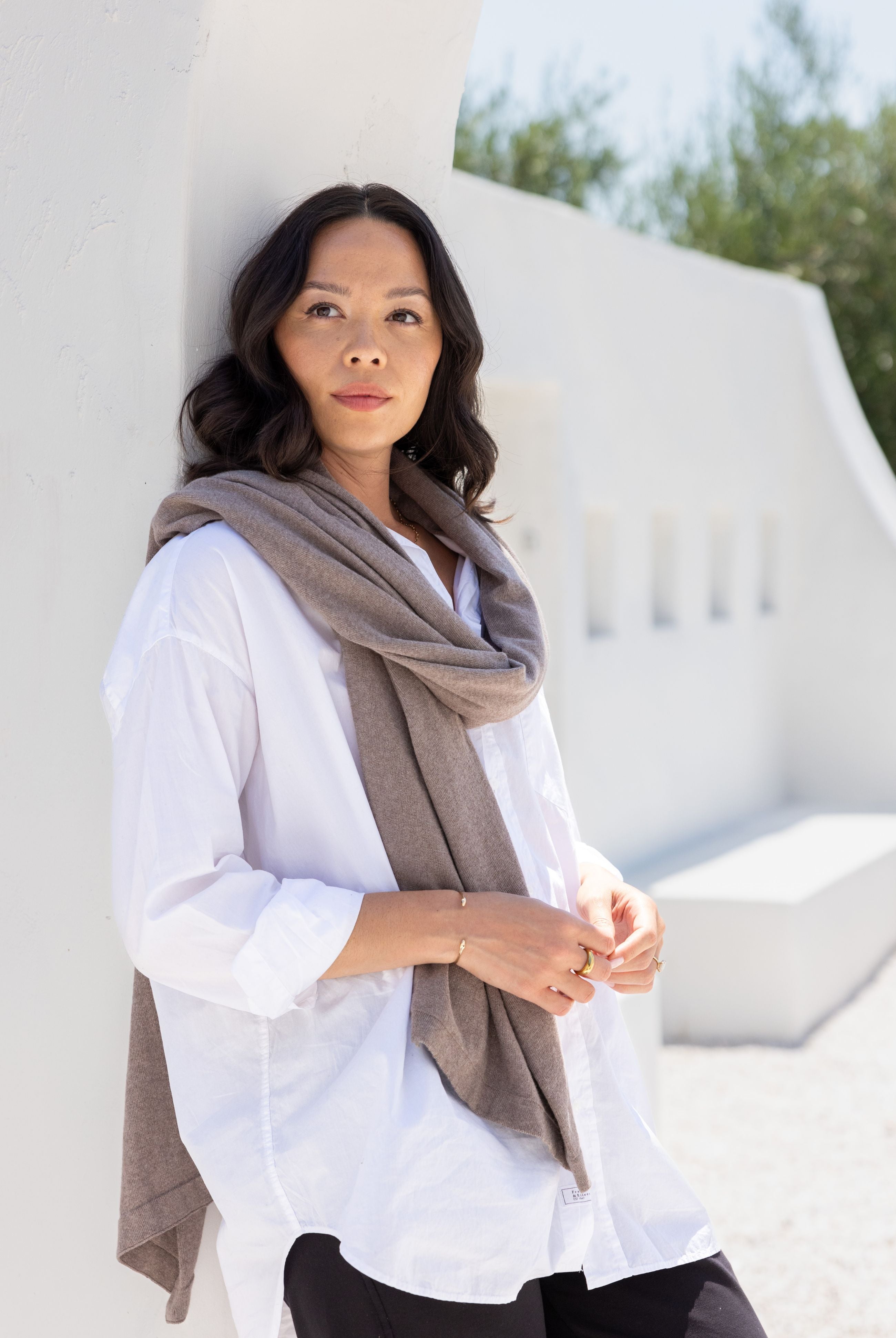 Women shown wearing a dark beige scarf wrapped around her neck